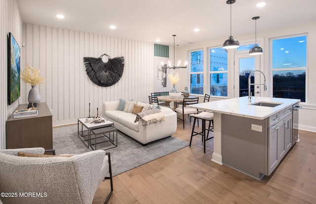 living room featuring an inviting chandelier, sink, and light hardwood / wood-style flooring