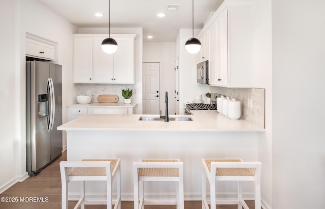 kitchen featuring a breakfast bar, stainless steel fridge, white cabinetry, and sink