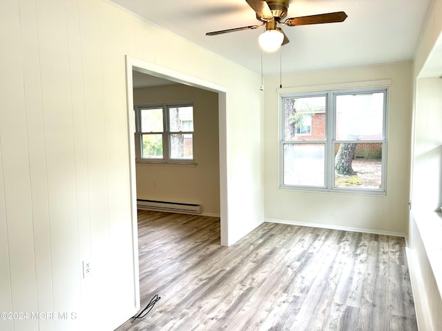 empty room with light wood-type flooring, a baseboard radiator, ceiling fan, and a healthy amount of sunlight