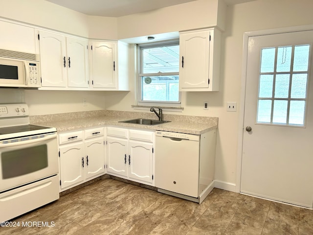 kitchen with a wealth of natural light, white cabinetry, sink, and white appliances