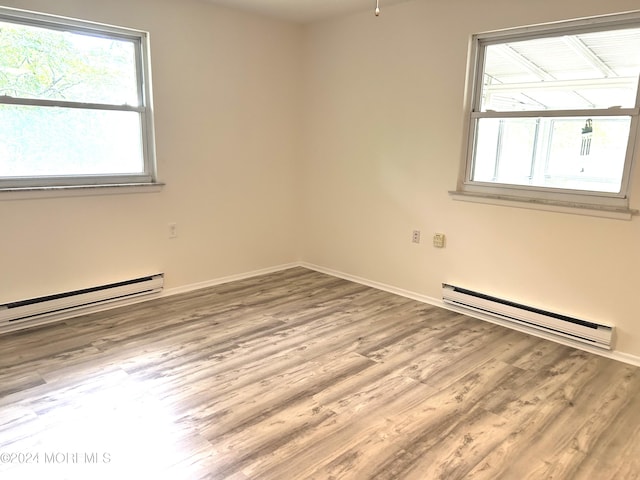 spare room with a baseboard radiator and light wood-type flooring