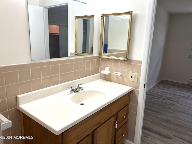 bathroom with decorative backsplash, hardwood / wood-style floors, vanity, and tile walls