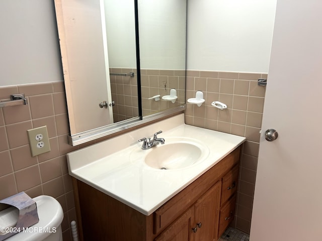 bathroom featuring vanity, tile walls, and toilet