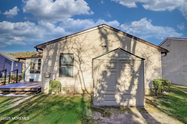 rear view of property with a yard, a wooden deck, and a shed