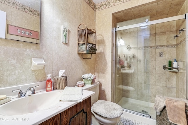 bathroom with toilet, vanity, and a shower with shower door