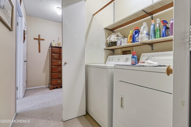 laundry area with washer and dryer, a textured ceiling, and light carpet