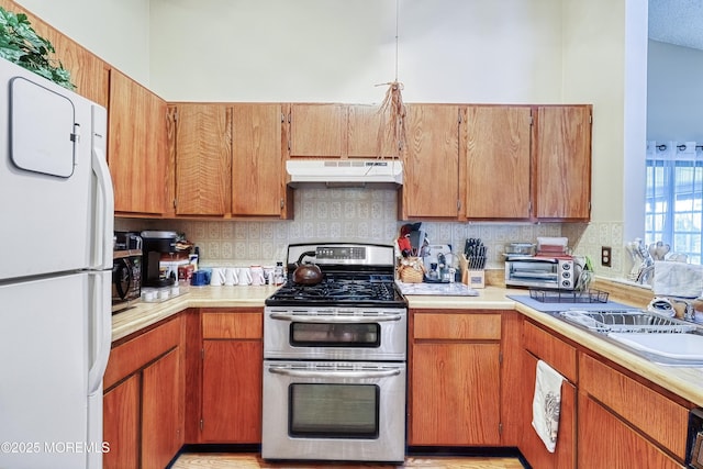 kitchen featuring sink, white refrigerator, double oven range, and backsplash