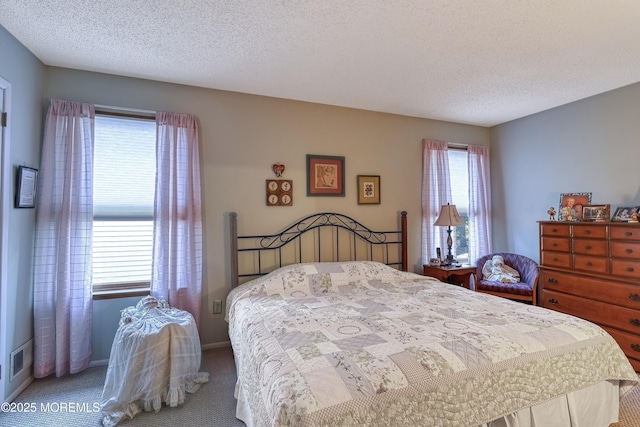 bedroom featuring a textured ceiling, multiple windows, and carpet flooring