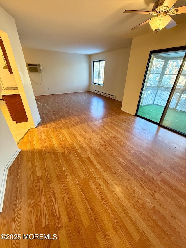 interior space with ceiling fan, baseboard heating, a wall mounted AC, and light hardwood / wood-style flooring