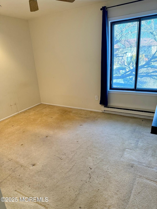 spare room featuring light carpet, a wealth of natural light, and a baseboard heating unit