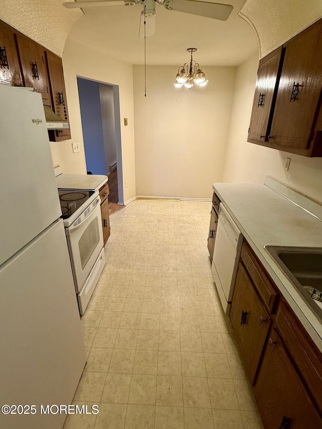 kitchen with white appliances, ceiling fan with notable chandelier, decorative light fixtures, and sink