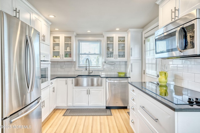 kitchen with white cabinets, sink, appliances with stainless steel finishes, and light hardwood / wood-style flooring