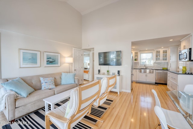 living room with sink, high vaulted ceiling, and light hardwood / wood-style flooring