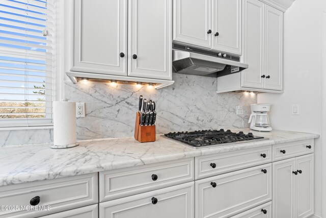 kitchen featuring light stone counters, white cabinets, tasteful backsplash, and stainless steel gas cooktop