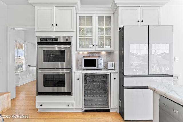 kitchen with white appliances, light stone countertops, light hardwood / wood-style floors, white cabinetry, and wine cooler