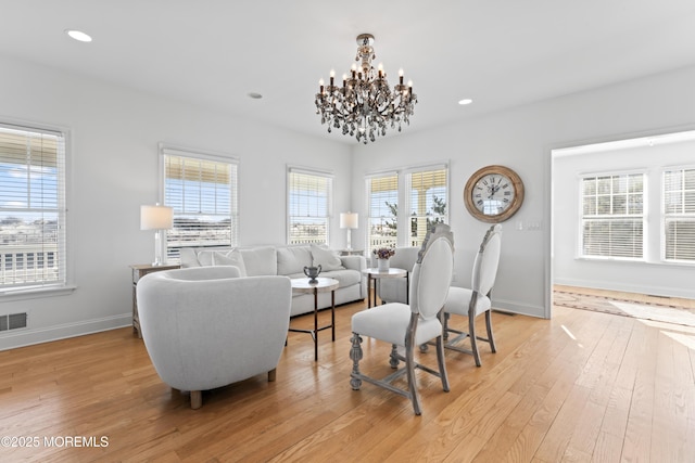 interior space featuring light hardwood / wood-style floors, a wealth of natural light, and an inviting chandelier