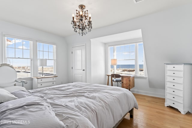 bedroom featuring a chandelier, multiple windows, and light hardwood / wood-style flooring