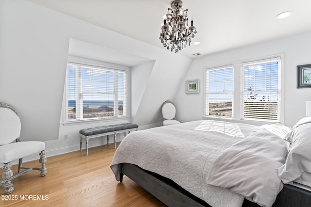 bedroom featuring a notable chandelier, hardwood / wood-style flooring, and lofted ceiling