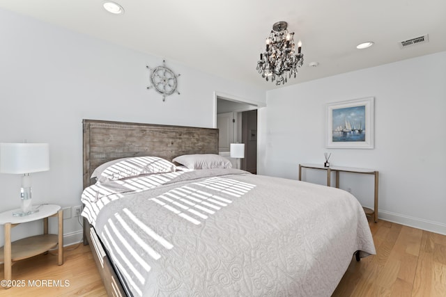 bedroom with a chandelier and light wood-type flooring