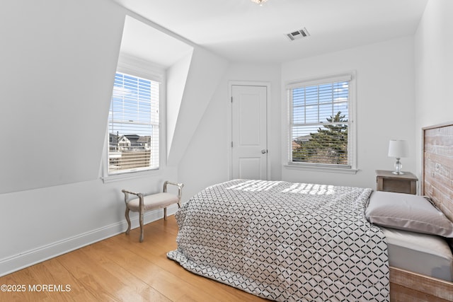 bedroom with multiple windows and hardwood / wood-style floors