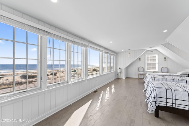 bedroom featuring hardwood / wood-style floors, a water view, and vaulted ceiling