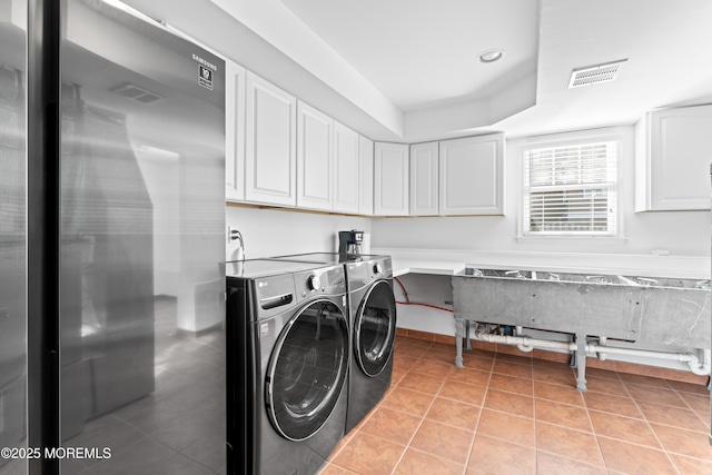 laundry room with cabinets, light tile patterned floors, and separate washer and dryer