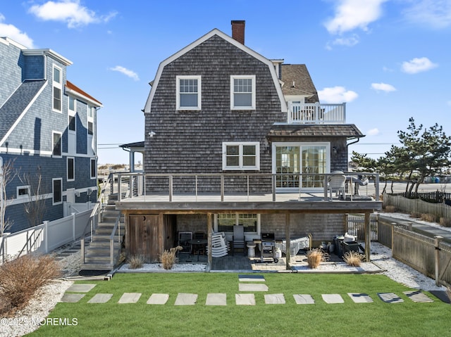 rear view of house with a balcony, a wooden deck, a patio area, and a yard