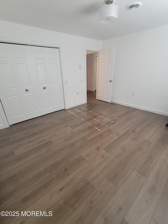 unfurnished bedroom featuring dark wood-type flooring and a closet