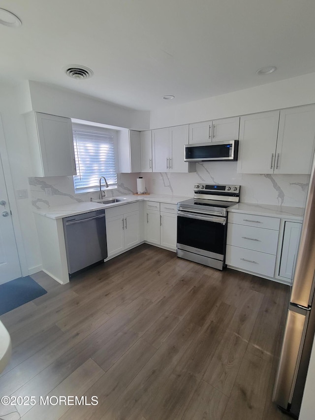 kitchen with white cabinets, appliances with stainless steel finishes, dark hardwood / wood-style flooring, and sink