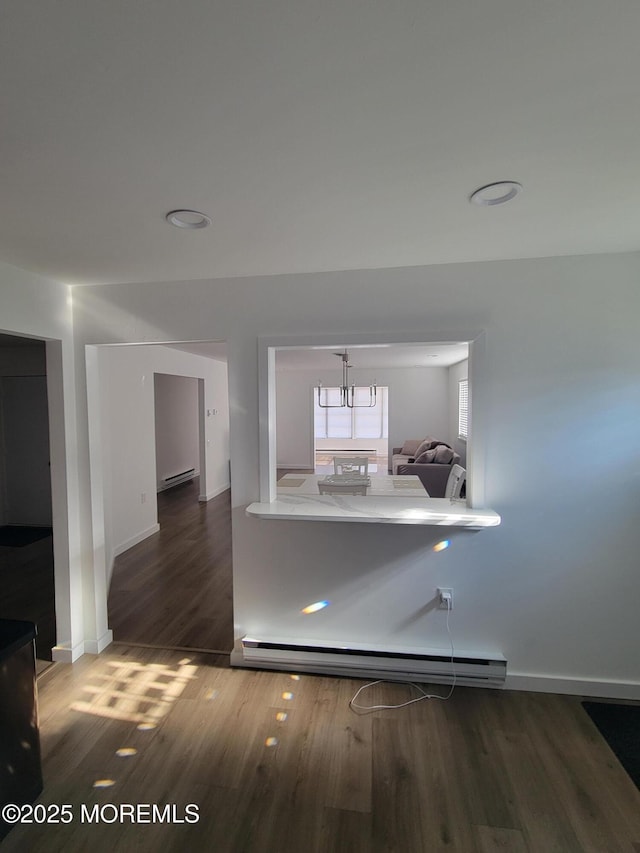 corridor with a baseboard radiator and dark hardwood / wood-style floors