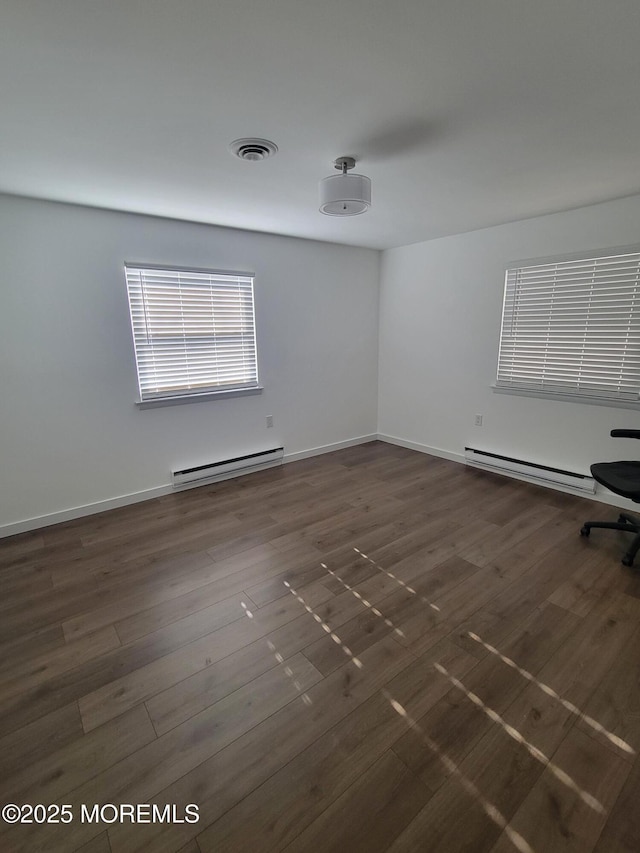 spare room featuring dark hardwood / wood-style flooring and a baseboard heating unit