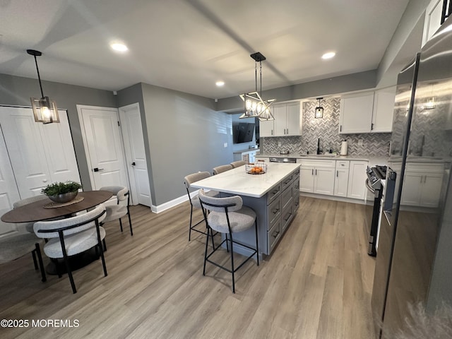 kitchen featuring white cabinetry, a center island, light stone counters, decorative light fixtures, and a breakfast bar area