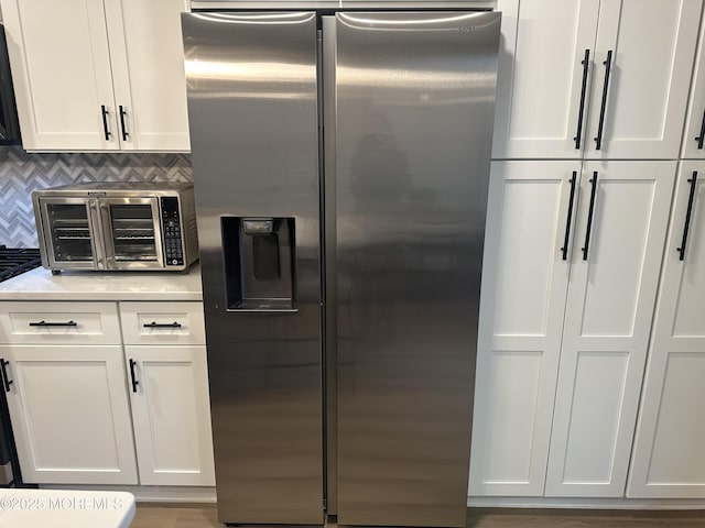 kitchen featuring white cabinets, stainless steel fridge with ice dispenser, and tasteful backsplash