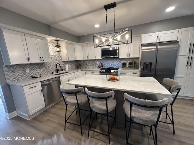 kitchen with pendant lighting, a kitchen island, white cabinets, and stainless steel appliances