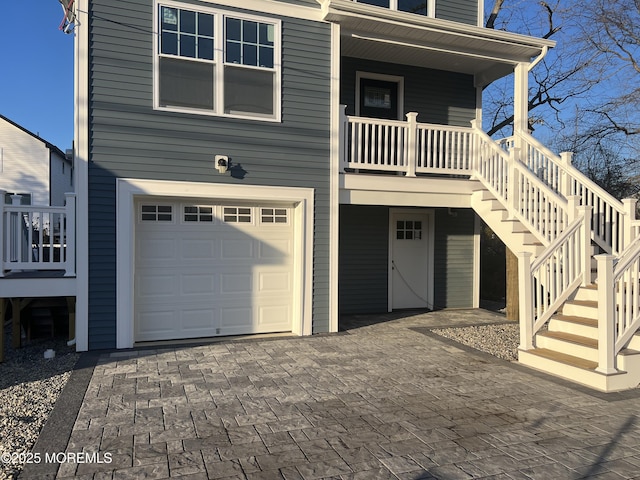 view of front of property with decorative driveway, covered porch, an attached garage, and stairs