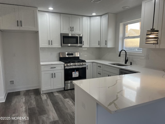 kitchen with appliances with stainless steel finishes, a sink, light stone counters, and white cabinets