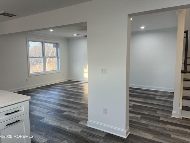 empty room featuring dark wood-style floors, visible vents, baseboards, and recessed lighting