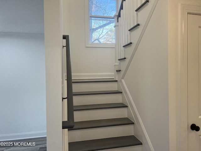 staircase featuring baseboards and wood finished floors