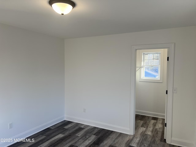 spare room featuring baseboards and dark wood finished floors