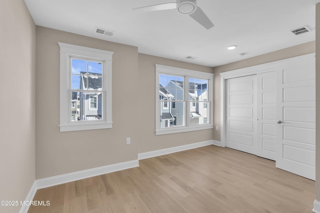 unfurnished bedroom featuring a closet, multiple windows, and light wood-type flooring