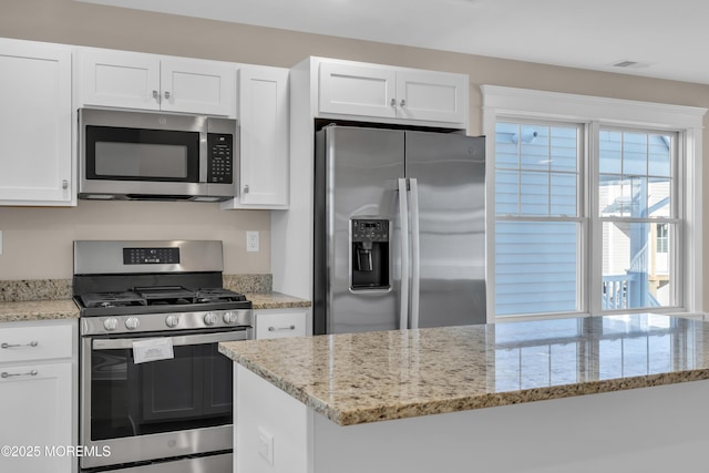 kitchen with light stone countertops, white cabinets, and appliances with stainless steel finishes