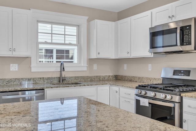 kitchen featuring appliances with stainless steel finishes, sink, white cabinets, and light stone counters