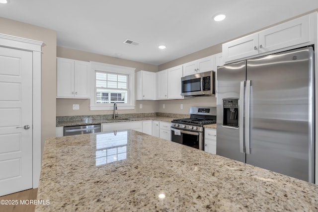 kitchen with white cabinetry, light stone counters, and stainless steel appliances