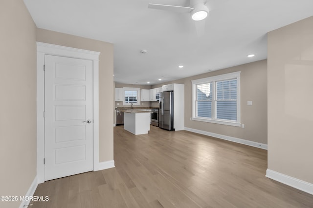 unfurnished living room featuring ceiling fan, light hardwood / wood-style floors, and a wealth of natural light