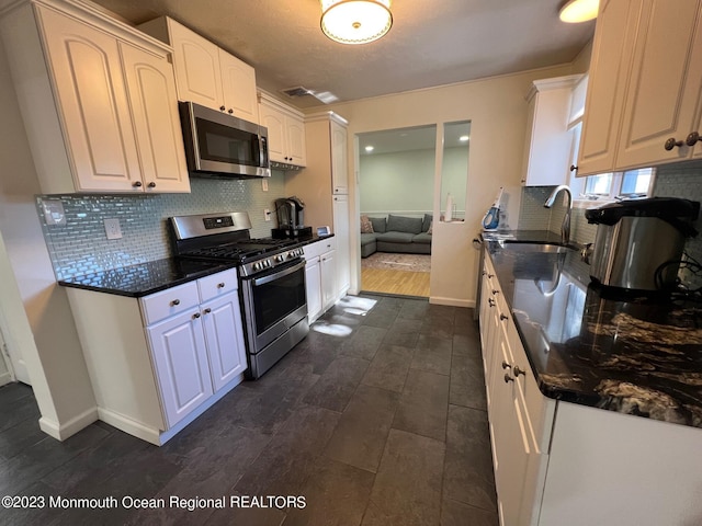 kitchen featuring white cabinets, sink, stainless steel appliances, and tasteful backsplash