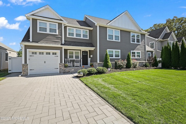 view of front of property featuring a porch, a garage, and a front lawn