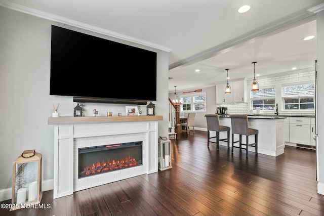 living room featuring dark hardwood / wood-style floors, crown molding, and a chandelier