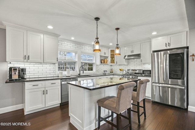 kitchen with stainless steel appliances, a kitchen island, sink, decorative light fixtures, and white cabinetry