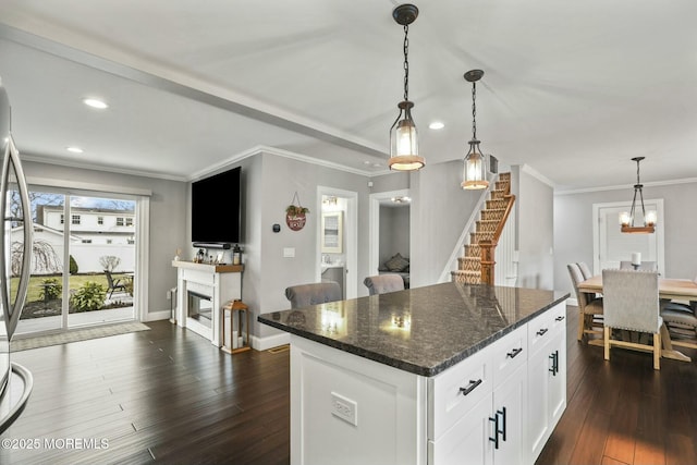 kitchen featuring a center island, dark wood-type flooring, white cabinets, dark stone countertops, and decorative light fixtures