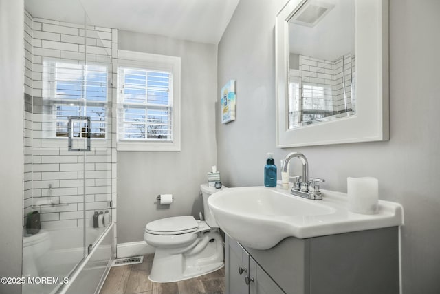 full bathroom featuring toilet, combined bath / shower with glass door, and vanity